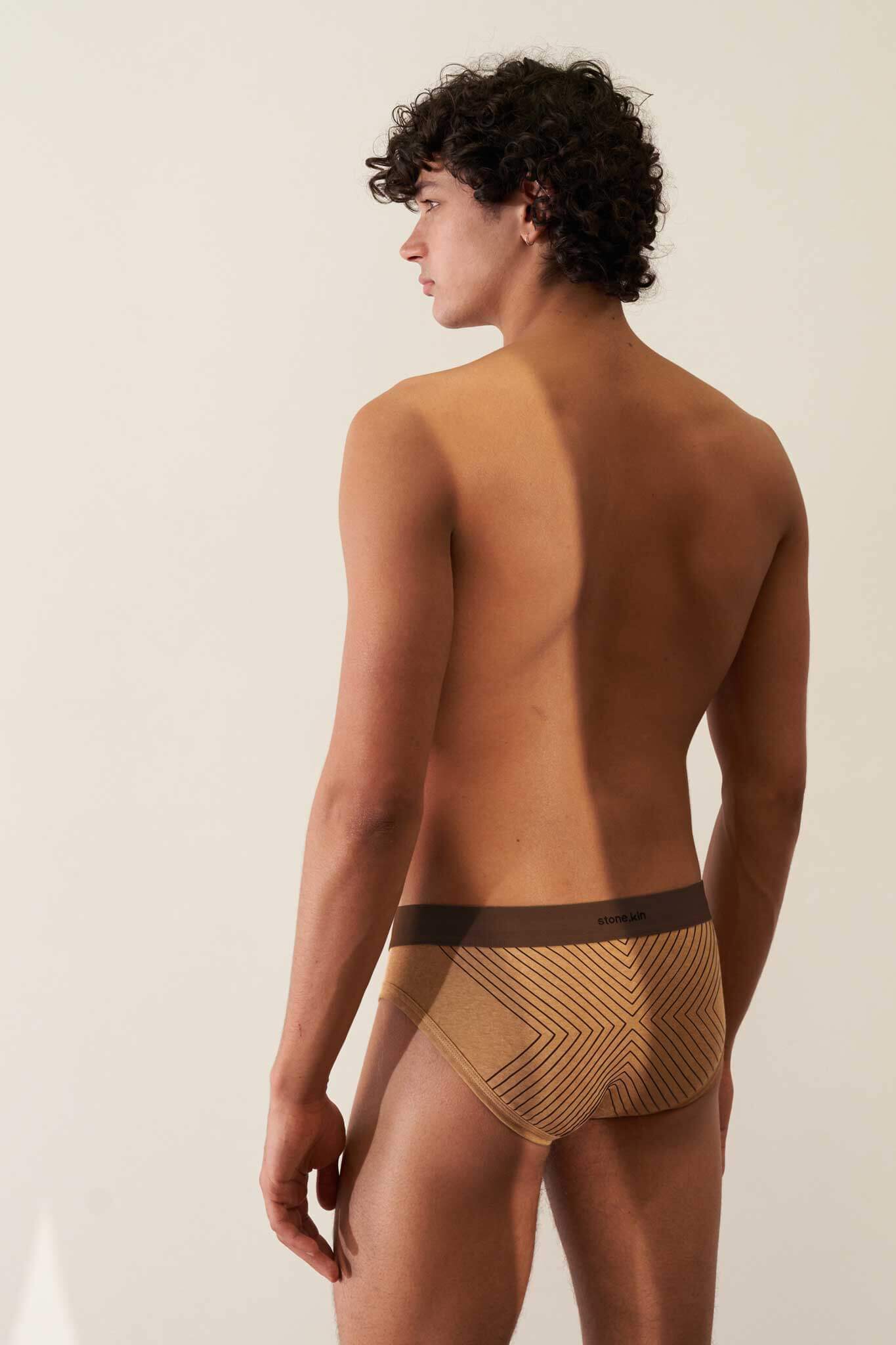 Male model wearing camel organic cotton rib briefs with a brown waistband, showcasing comfort and non-toxic materials.