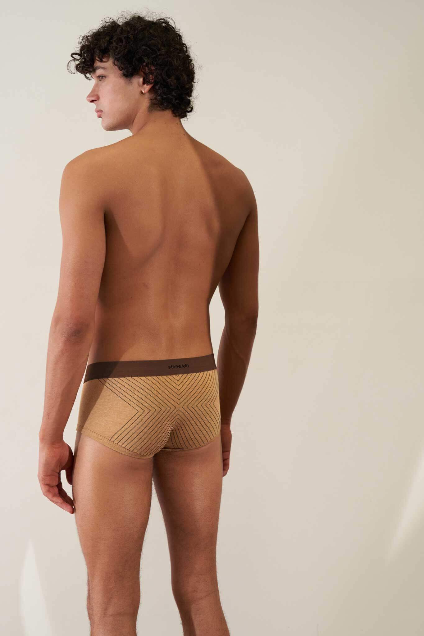 Man wearing organic cotton rib trunk in camel color with brown cross, showcasing comfort and GOTS certification.