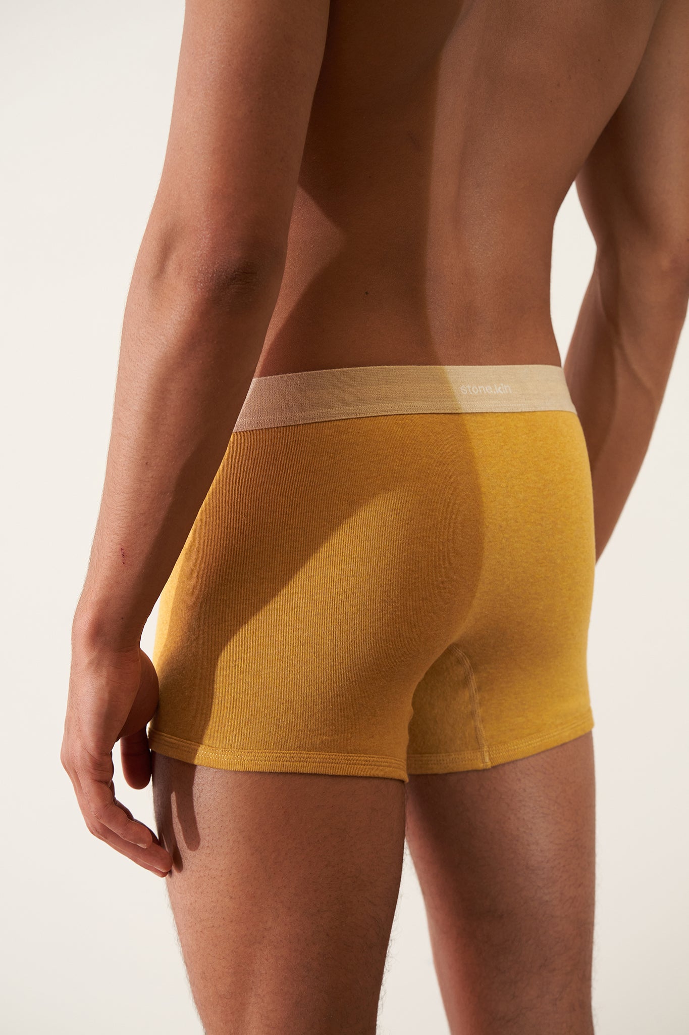 Boxer Brief in Organic Cotton Rib - Mustard / Sand displayed on a male model from the back, highlighting the rib texture.